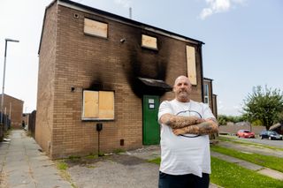 Andrew Beaton standing in front of his boarded up house after a e-bike lithium ion battery fire