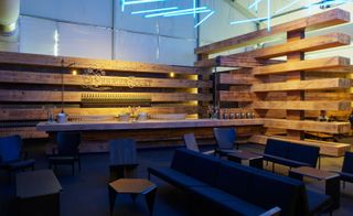 Seating area and bar surrounded by walls made from stacks of wood