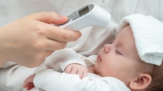 Baby having temperature taken with a forehead thermometer