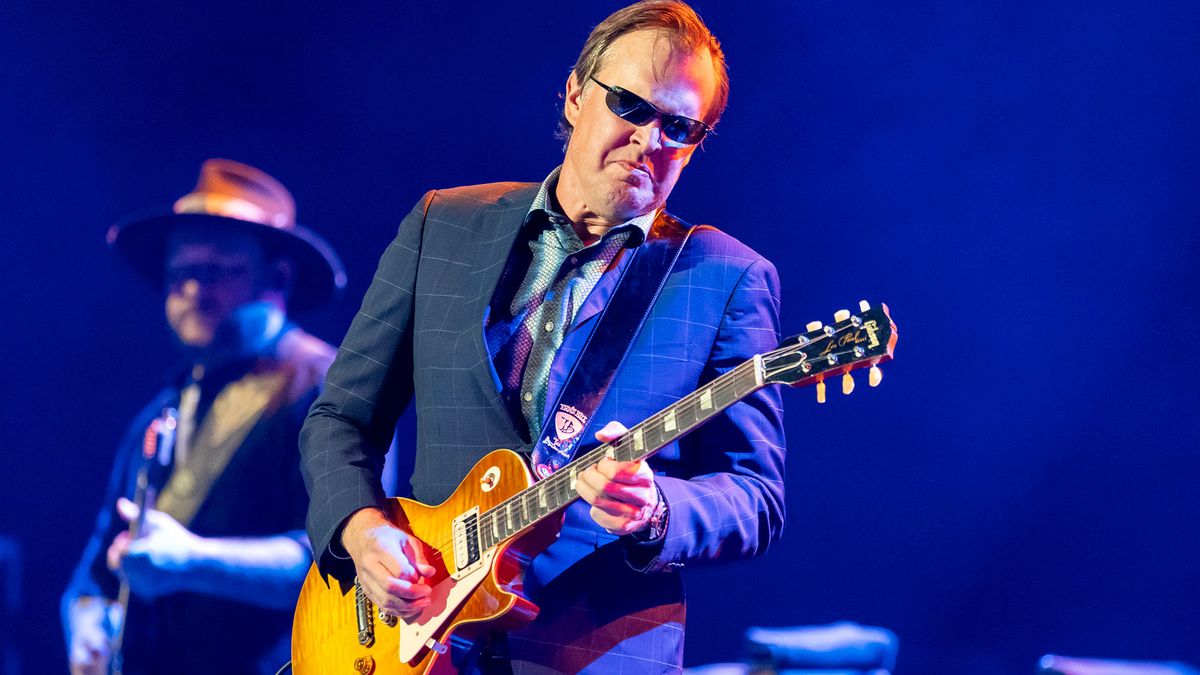 Joe Bonamassa wears sunglasses and a blue plaid suit while playing a 1959 Gibson Les Paul Standard onstage in 2023