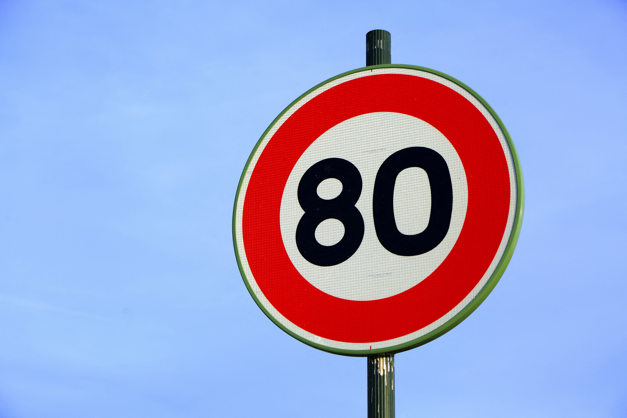 A road sign with the number 80 in a red circle, indicating the speed limit in kilometers.