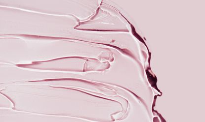 Closeup strokes of transparent cosmetic gel for spa procedure spread on bright pink background. Serum or antibacterial gel are the main products of the year