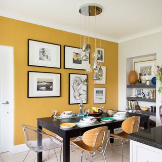 dining room with mustard yellow wall frames on wall and pendant lamps