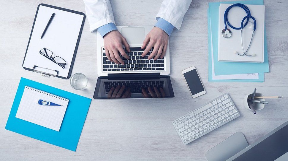 A person in a medical practice typing on a laptop.