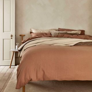 Rust-coloured bedding in a neutral bedroom