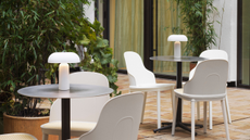 two small outdoor table with three white chairs and an outdoor lamp on each table