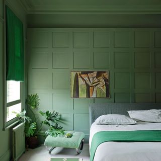 Green bedroom with large bed and artwork