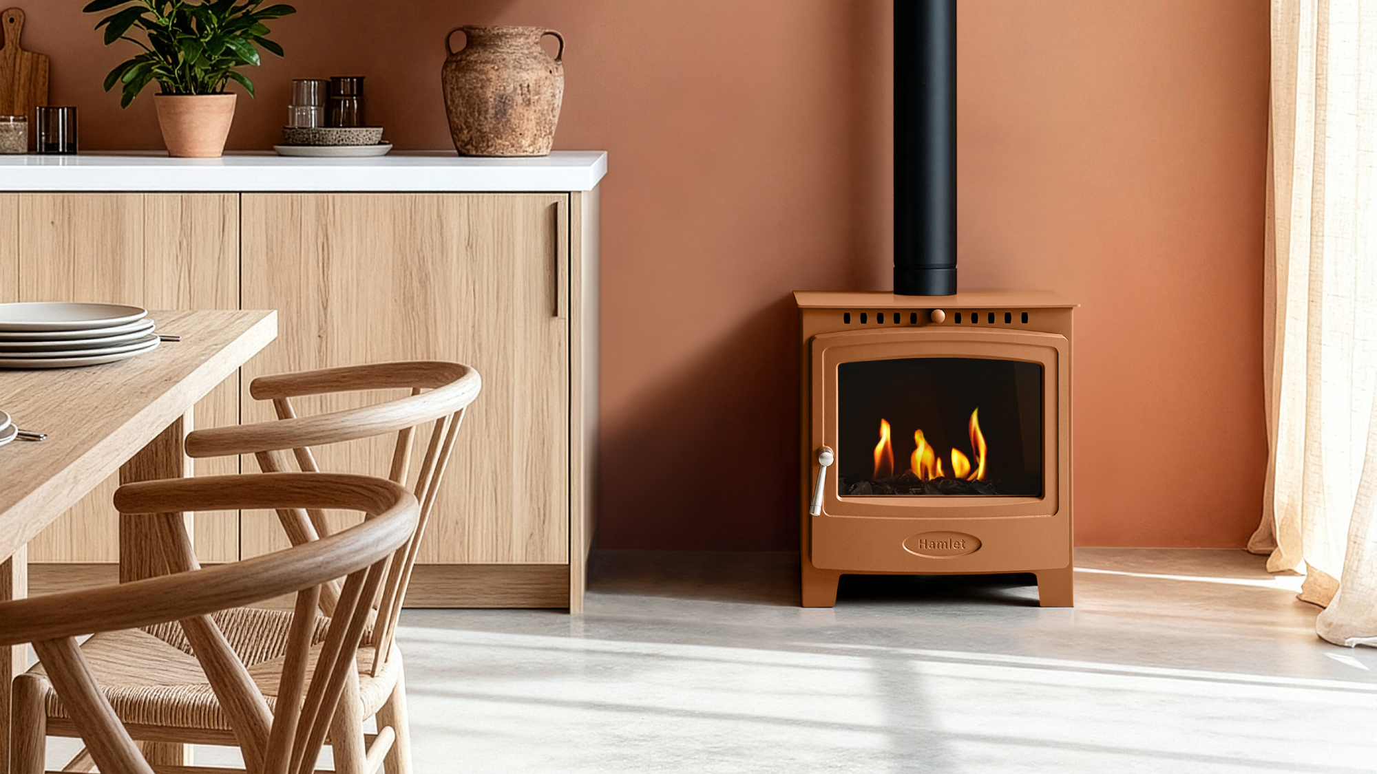 terracotta colour bioethanol stove with flue in a dining room with terracotta painted walls, light grey floor tiles, wooden sideboard and table and chairs