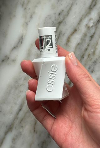 Holding Essie Gel Couture Top Coat Bottle