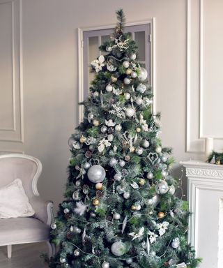 A large artificial Christmas tree with white ornaments and floral touches