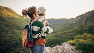 Woman holding a dog while hiking