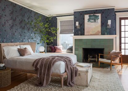 Bedroom with dark blue embroidered wallpaper and green tiled fireplace