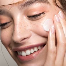 Model applying milky skincare products to her face