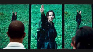 Jennifer Lawrence as Katniss doing three finger salute in The Hunger Games