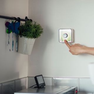 smart thermostat on a kitchen wall above a microwave and smart heater