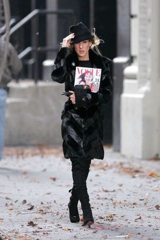 Carrie Bradshaw wearing black coat and hat