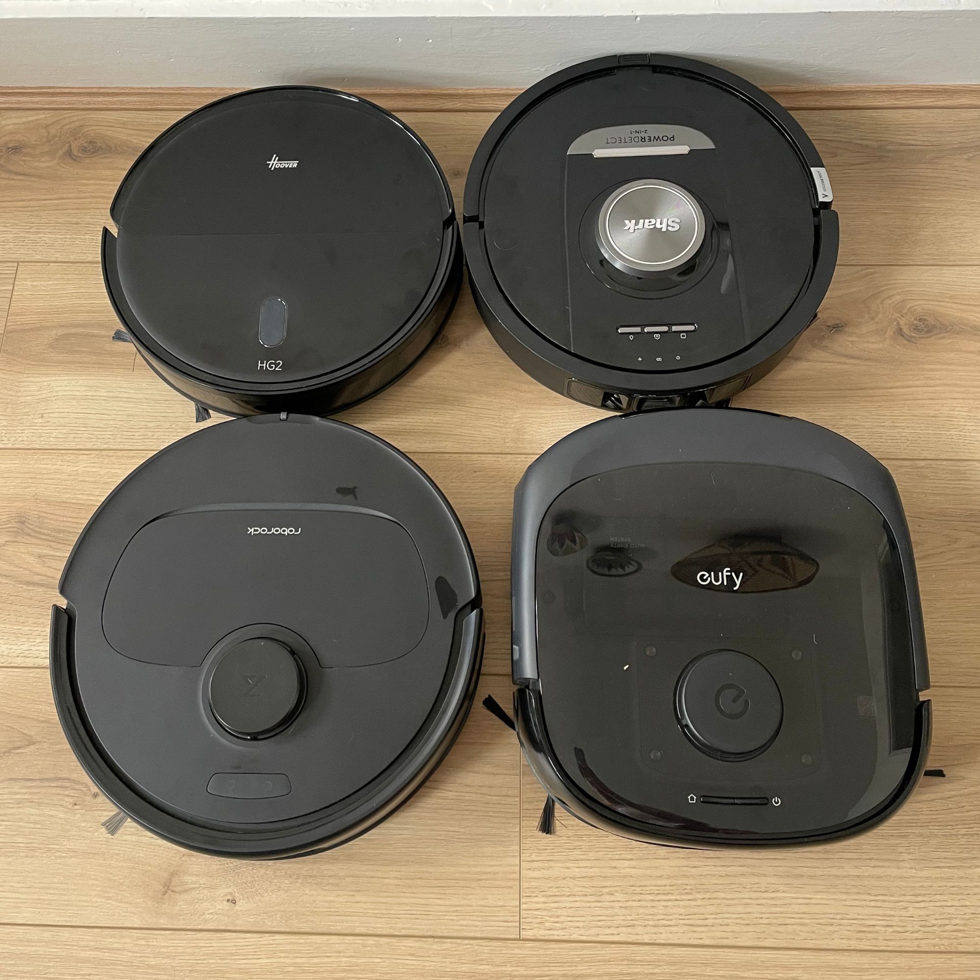 Four robot vacuums sitting next to each other on wood-effect flooring