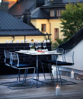 A small outdoor dining table on a rooftop, with small candles on the ground