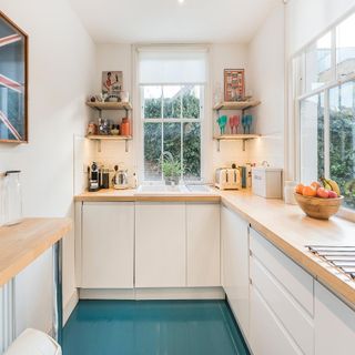 kitchen area with wooden counter and white wall and blue painted floor