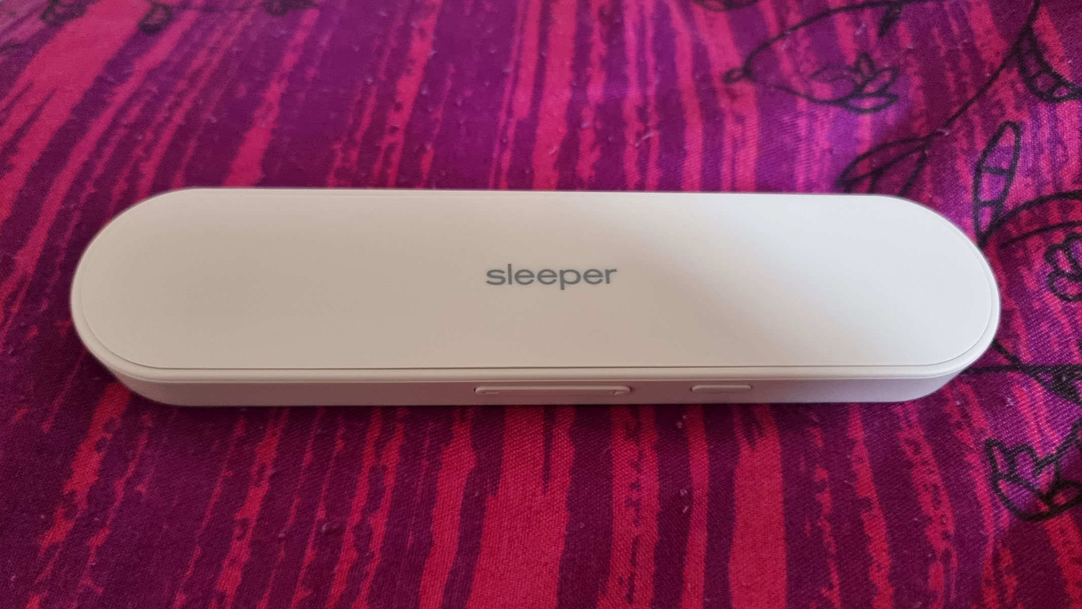 A close-up picture of our reviewer's Advanced Sound Group Sleeper Speaker lying on a pillow 