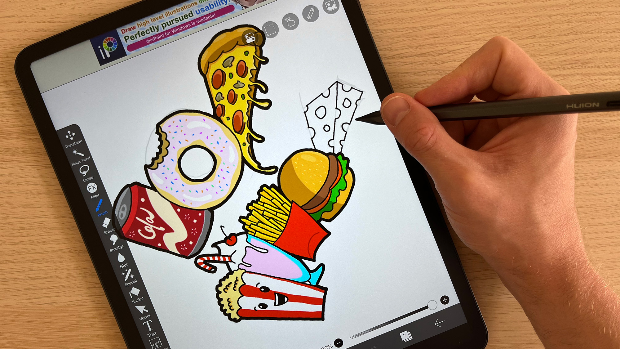 Hand using stylus to draw on Huion Kamvas Slate 13 on a wooden table 