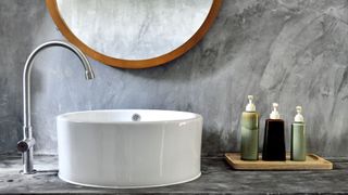Marble grey bathroom with contemporary round white sink basin with chrome arch tap and round wooden framed mirror