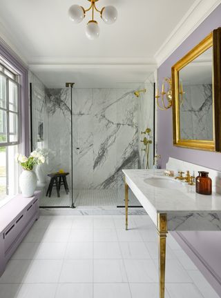 A lavender bathroom with a gold mirror