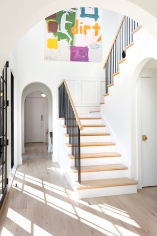 white hallway with modern staircase and artwork on the wall