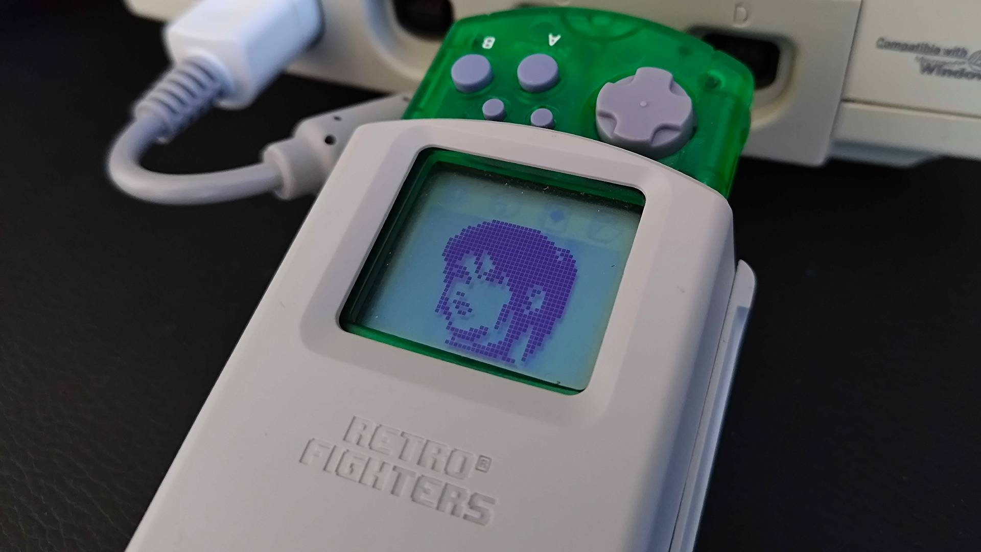 Close up of Retro Fighters StrikerDC VMU cradle connected to console with Claire Redfield sprite displayed.