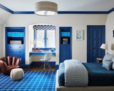 Bedroom ideas for boys with white walls, blue painted accents, a built-in blue desk in the alcove window and a chair shaped like a baseball mit
