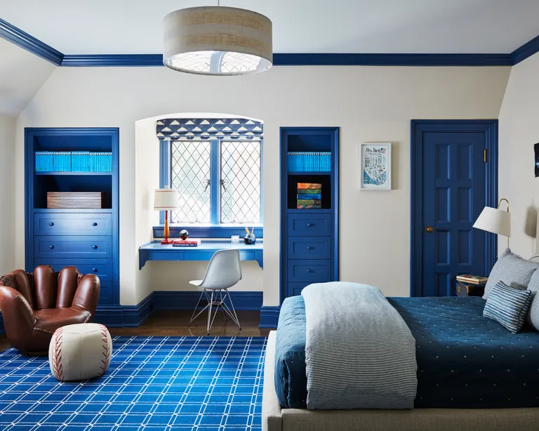 A child's bedroom with white wall, blue painted accents and a chair shaped like a baseball mit