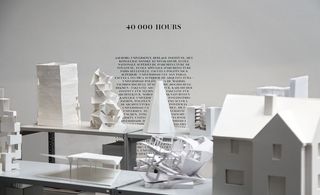 Miniature white sculptures against a white wall with black texts