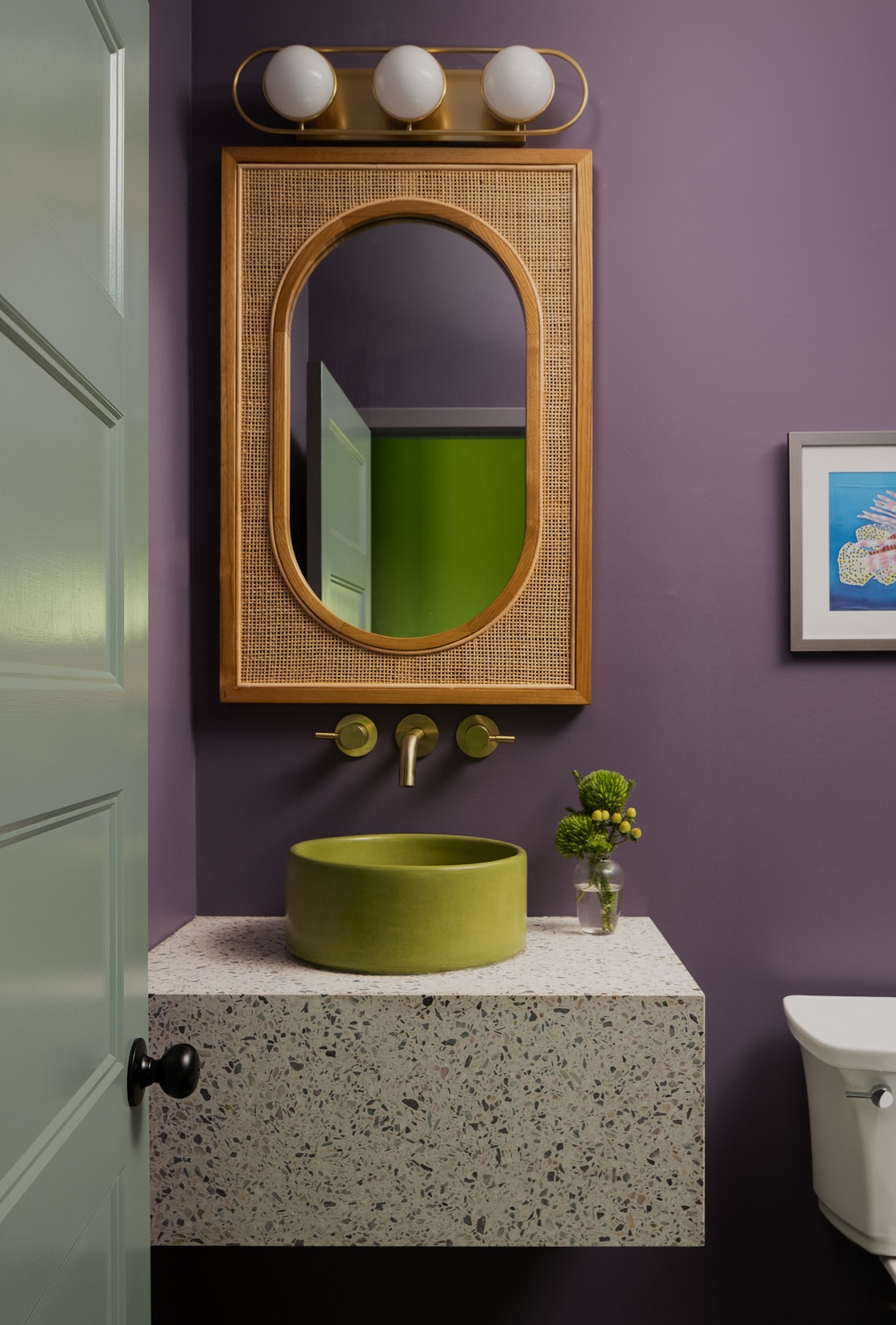 A contemporary bathroom with purple walls and bright green washbasin