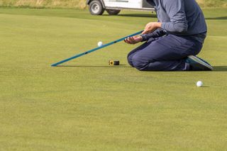 A stimpmeter being used on a green