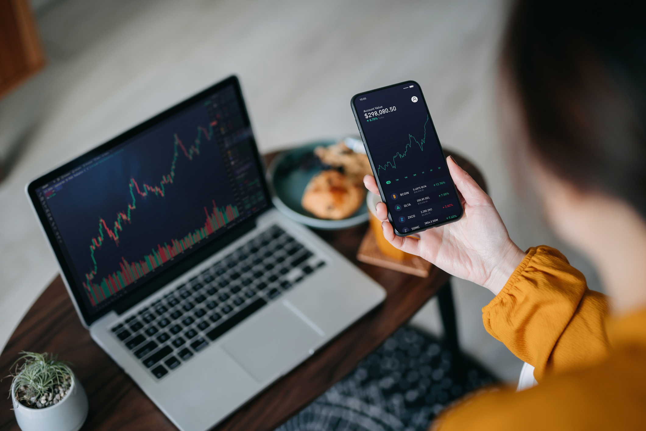Over the shoulder view of woman holding smartphone, analyzing investment trading data.
