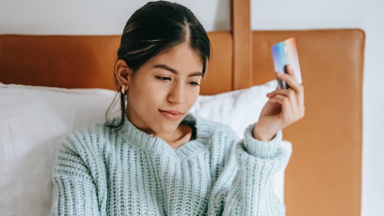 A woman holding a gift card and looking at a laptop screen