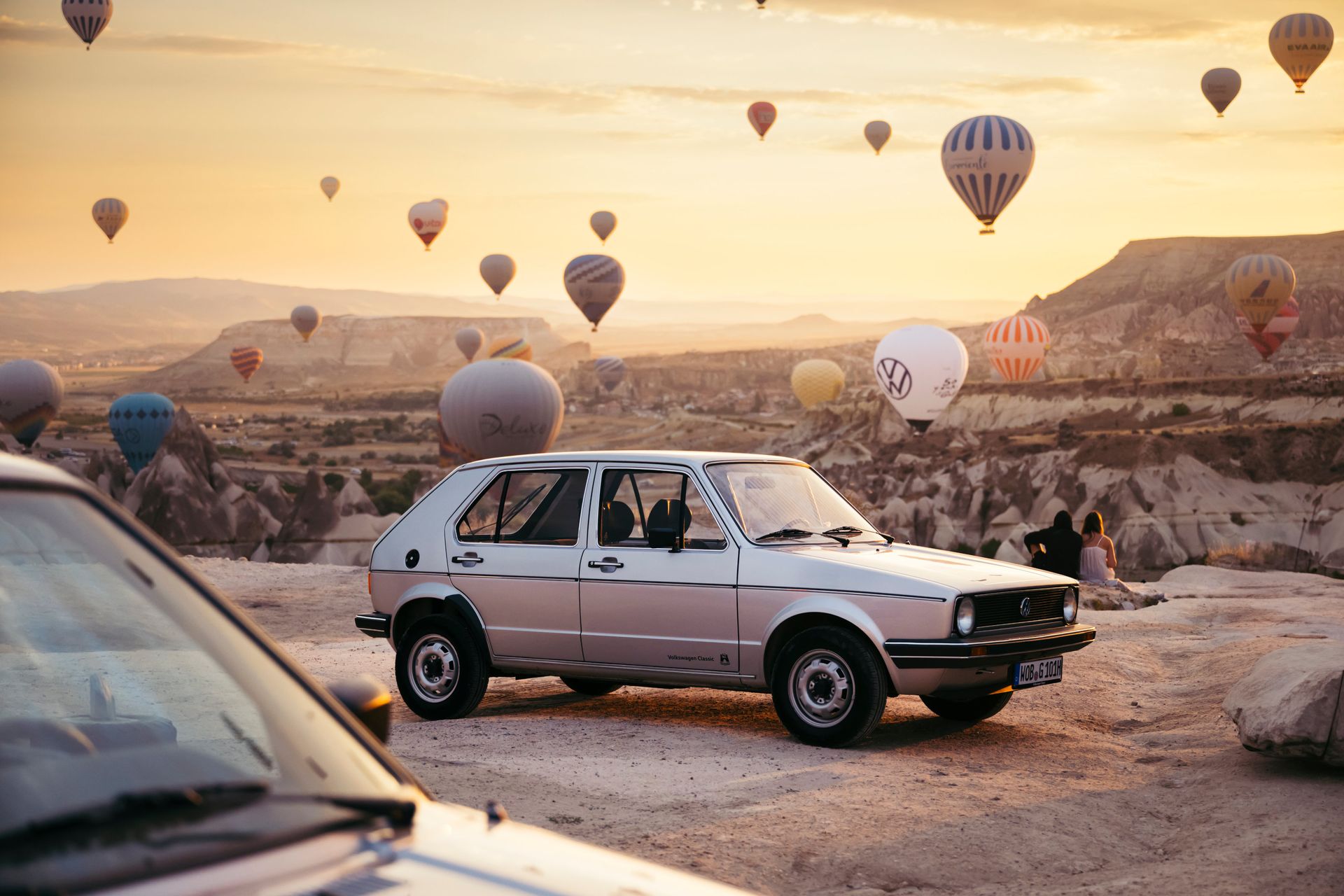 VW golf in rocky landscape with hot air balloons