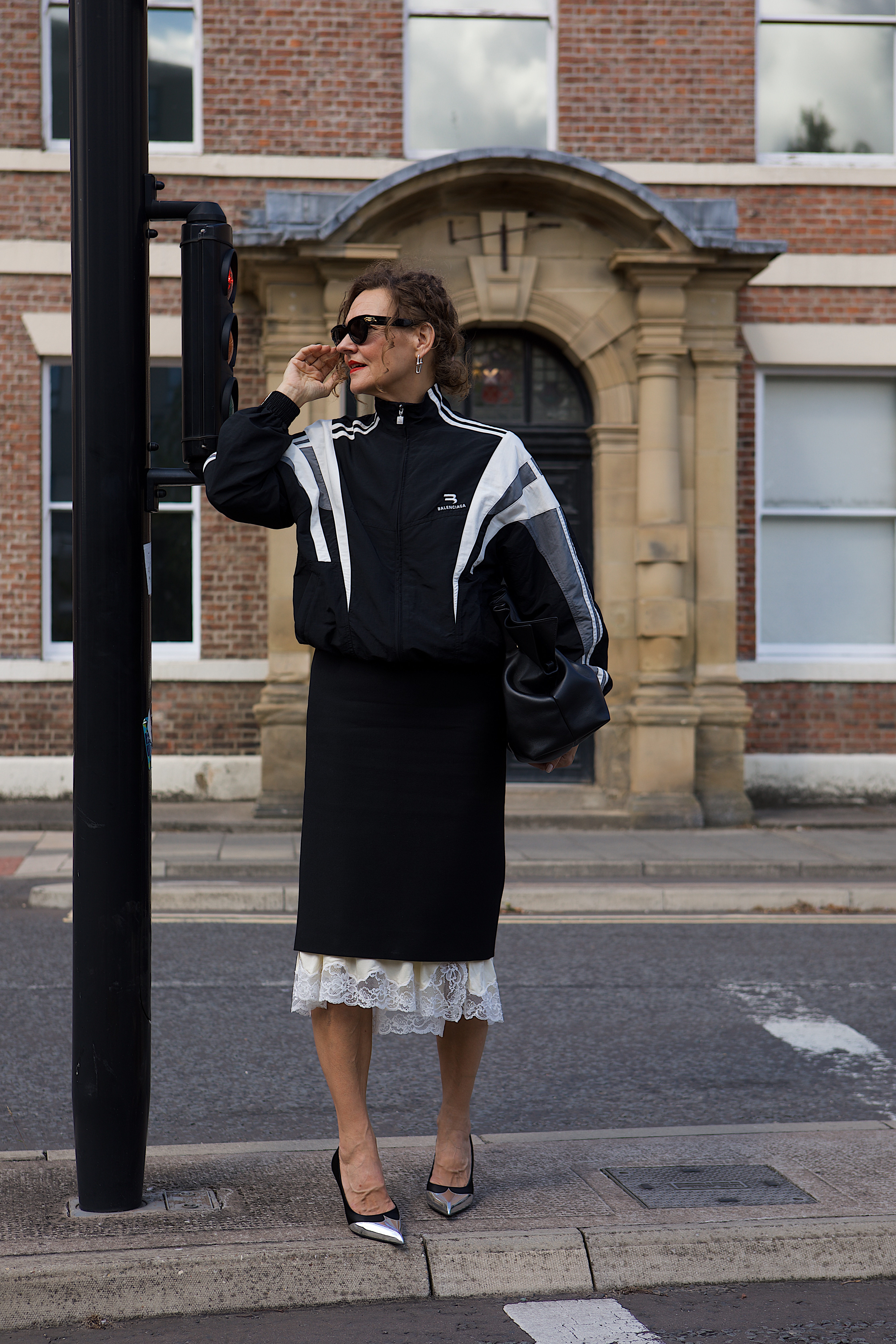 Renia Jaz wearing a sporty sweatshirt, a lace-trimmed skirt, heels, and a slouchy bag