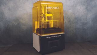 An Anycubic Photon M3 Premium printer in front of a grey textured background