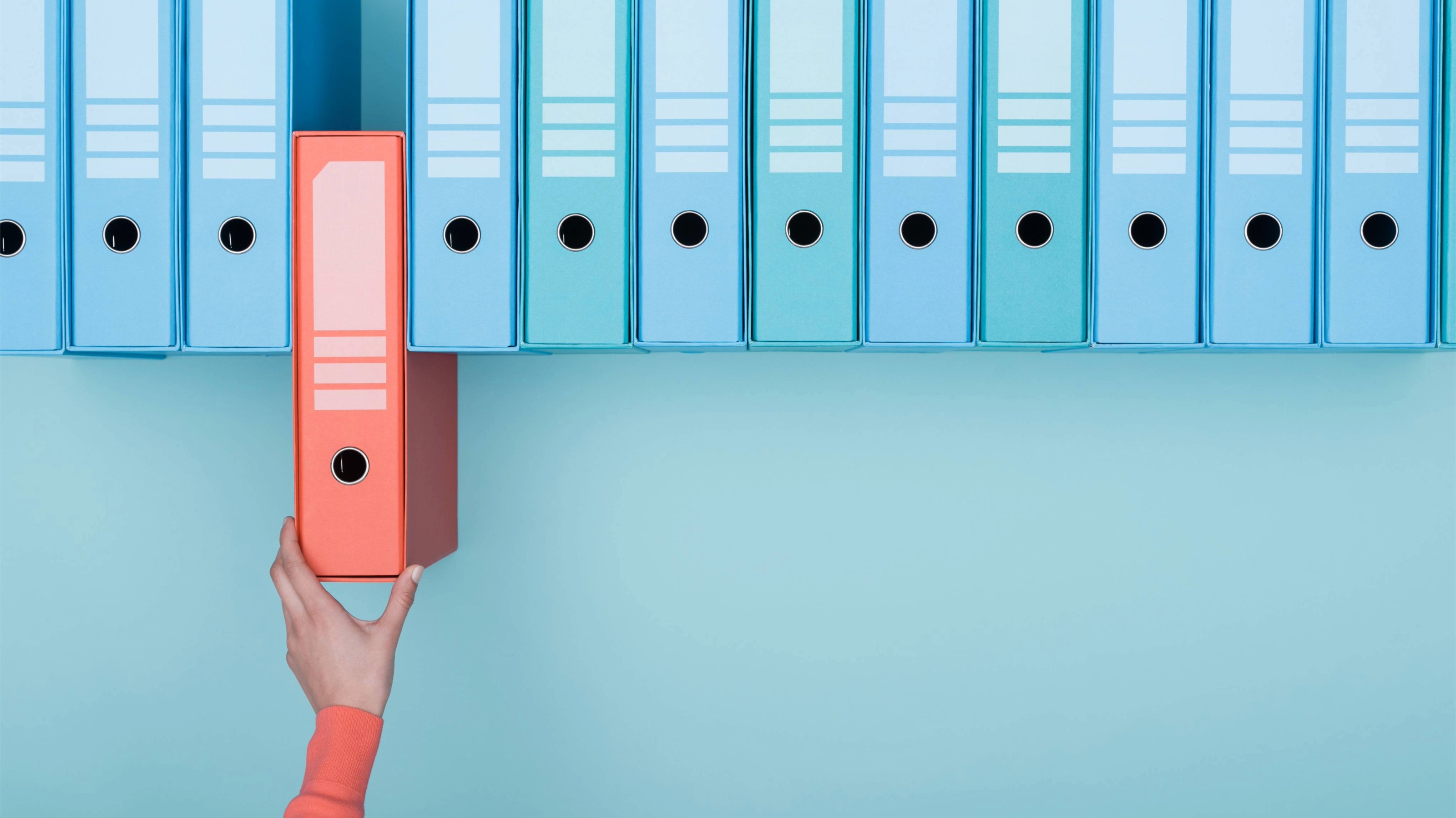 Office worker taking a red folder from an archive of blue folders