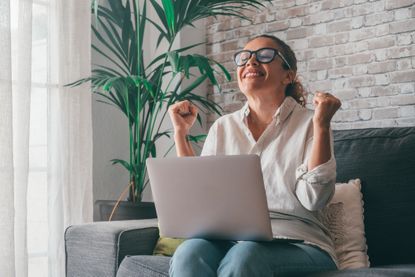 Woman Using Laptop While Sitting On Sofa At Home