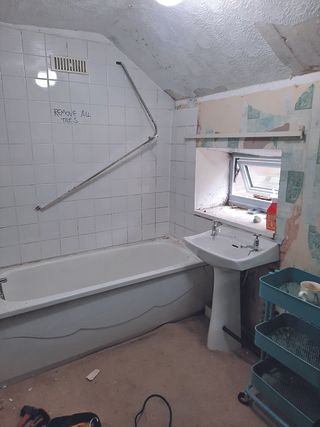 Before shot showing bathroom with brown carpet, plain white wall tiles and bath-shower