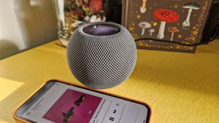 Apple HomePod Mini on a cabinet with an iPhone