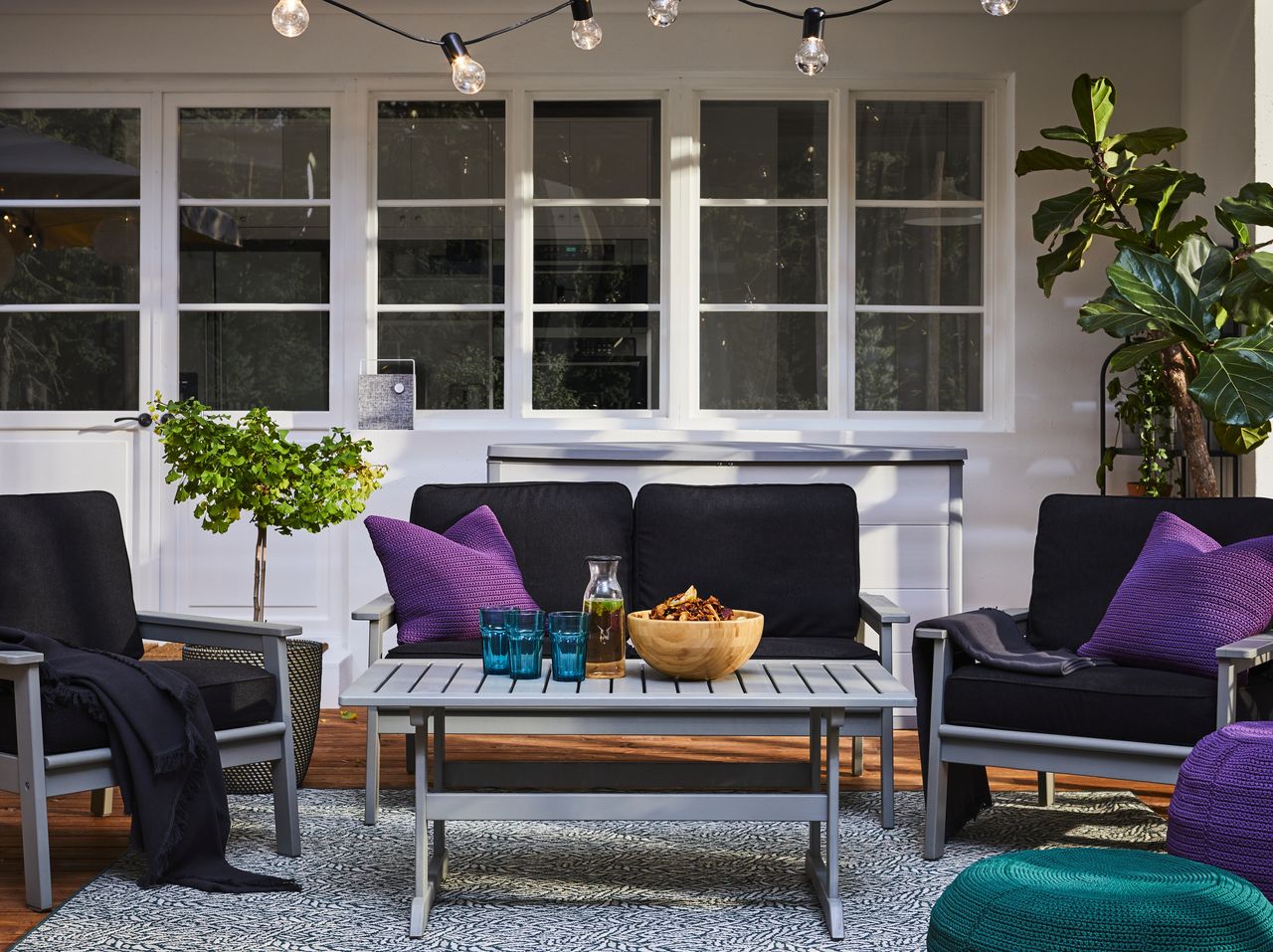 A small decking area with outdoor furniture and string lights