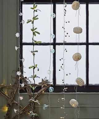 Christmas window decor ideas with numerous different styles of fairy light hanging vertically from the top of the window