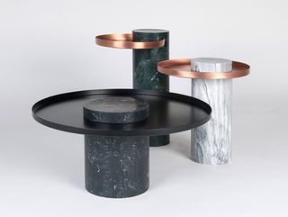 View of three black, white and dark green marble 'Salute' tables with round black and copper tops pictured against a light grey background
