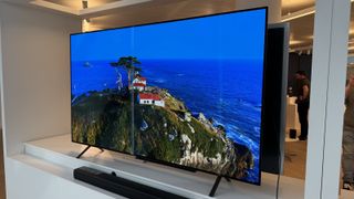 The LG B4 OLED photographed on a white shelf in a showroom. On the screen is an aerial shot of a lighthouse