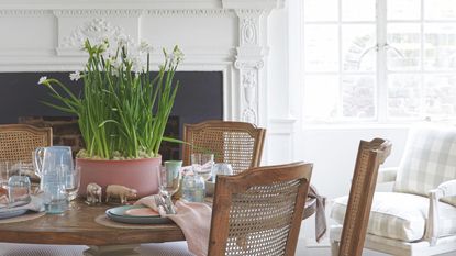 Table set up with pastel plates and napkins with a pink pot of daffodils in the centre