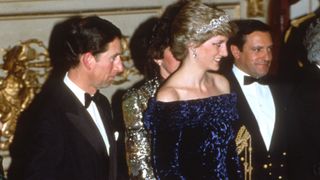 LISBON, PORTUGAL - FEBRUARY 11: Prince Charles, Prince of Wales and Diana, Princess of Wales, wearing a purple crushed velvet off the shoulder gown with matching shoes designed by Bruce Oldfield, the Spencer family tiara and diamond and sapphire earrings, attend a banquet at Ajuda Palace on February 11, 1987 in Lisbon, Portugal.
