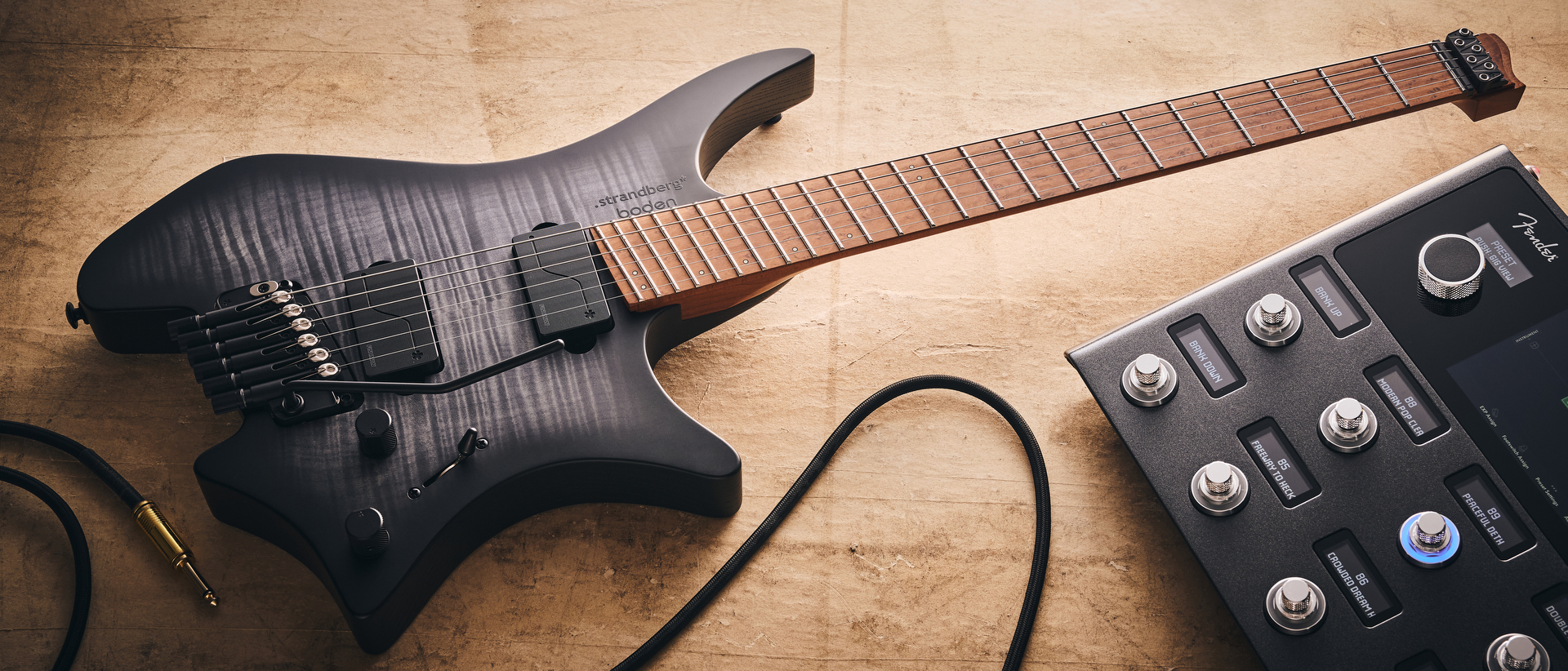 A Strandberg Boden Original N2.6T headless electric guitar on the floor with a Fender Tone Master amp modeler
